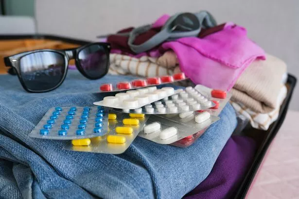 Women's clothing and pills in a travel bag. Concept of medication required in journey