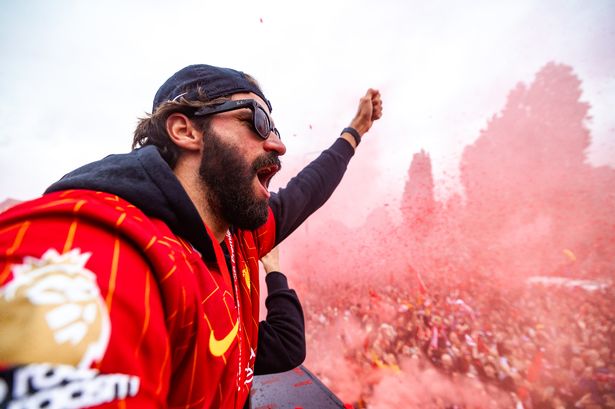 Alisson Becker celebrates as the team bus passes through fans in celebration during the Liverpool Premier League trophy parade on May 26 2025