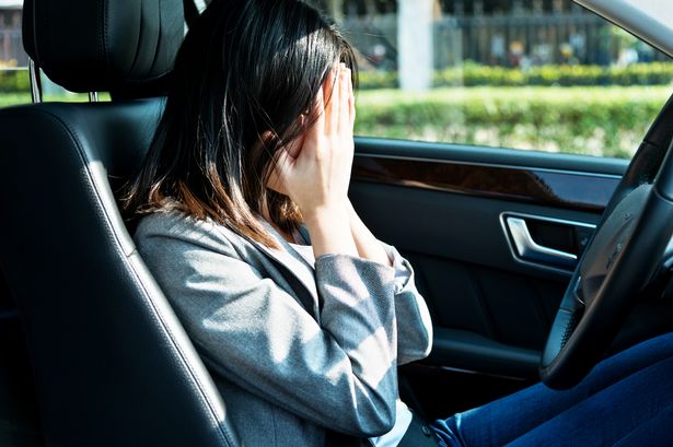 Woman in car, holding head in hands