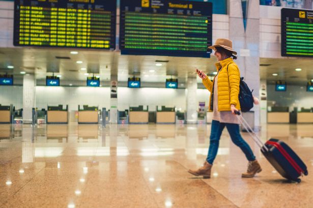 Tourist with suitcase at the airport walking and texting
