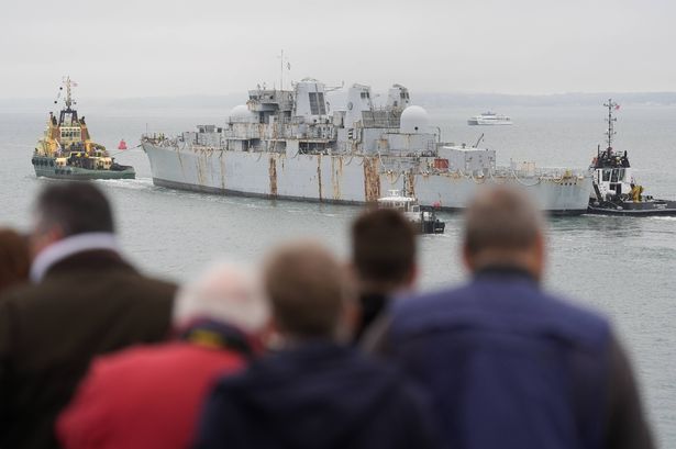 People watching from the shore as HMS Bristol is towed away