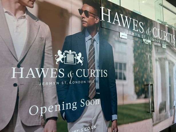 Photo shows boards outside shop showing men in suits