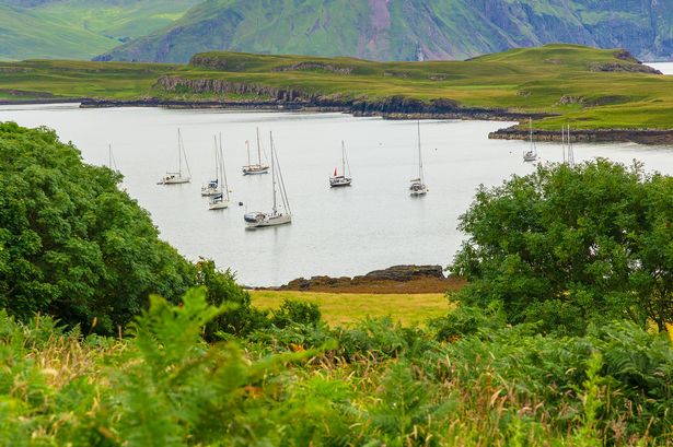 Isle of Canna in the inner Hebrides, Scotland.  A tranquil harbour with moored yachts and the larger Isle of Rum in the background.  Horizontal.  Copy space.