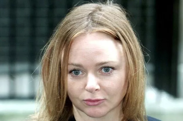 An image of a fair-haired woman wearing a black blazer, gazing away from the camera.