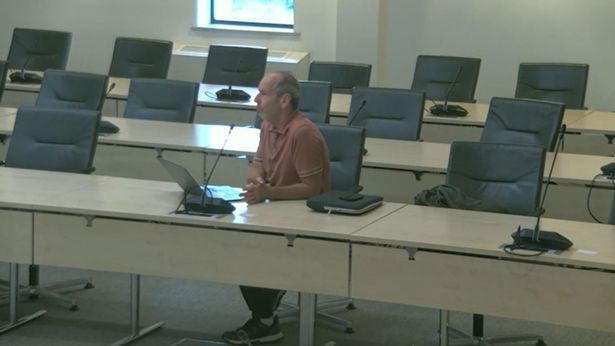 Man sat at desk at council meeting speaking into a microphone