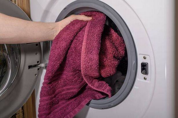 Putting a dirty towel into the washing machine close up
