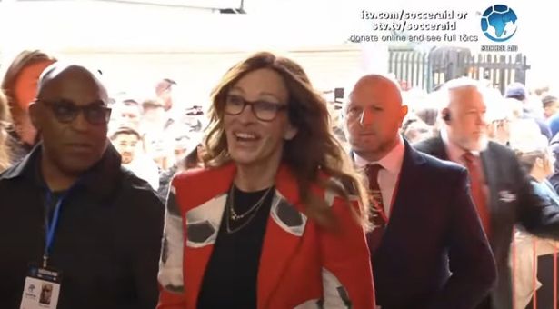 Julia then popped up on the camera as she was seen walking into the stadium, looking the part in a red blazer with large footballs printed all over it
