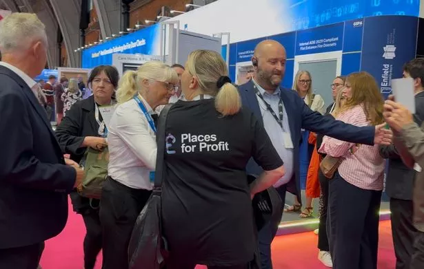 A Shaw tenant in a satirical T-shirt being forced out of the conference while protesting. 