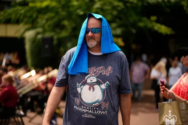 A person covers their head with a towel on a hot, sunny day
