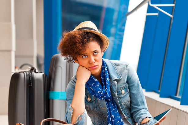 A bored teenaged girl waiting for her flight at the airport, holding a digital tablet in hand.