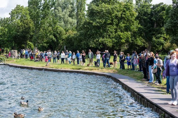 People in a line around a lake