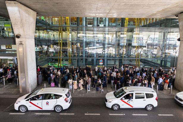 People queue for a taxi at an airport in Spain. 