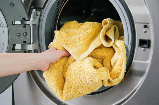 Putting yellow towel into a washing machine