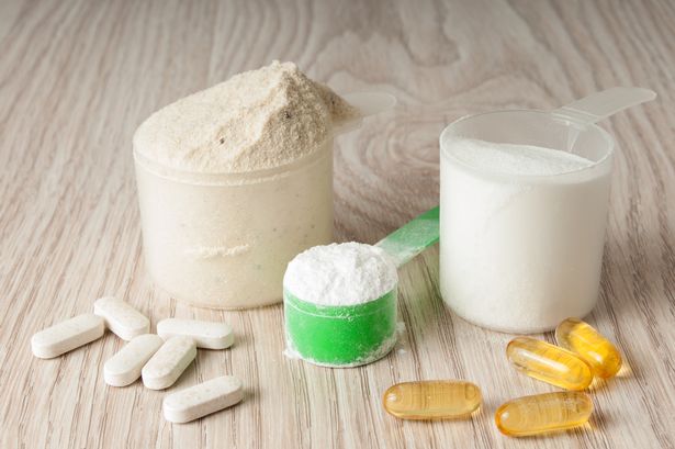 scoop of protein, bcaa and creatine, omega3 in pills on wooden background