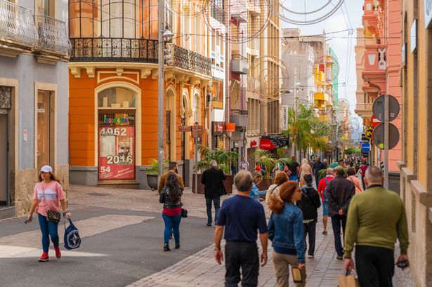 Tourist travellers waking down street in main area of Tenerife, Spain