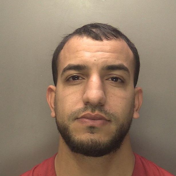 A police custody image of Younes Hairy who has short black hair and a black beard and is wearing a orange top 