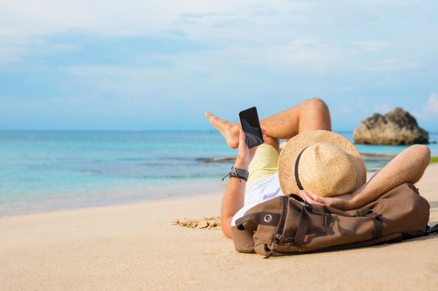 Guy with smartphone lying on the beach.