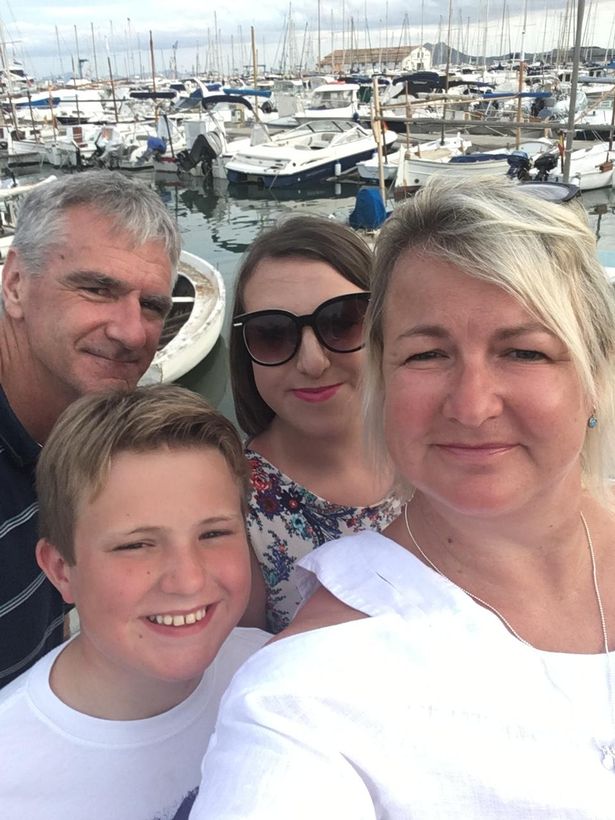 A family of four smiling  at a harbour