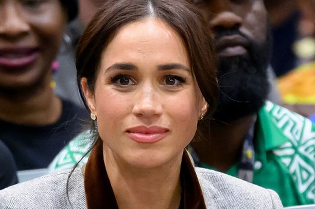 Meghan looks pensive and stares forward as she attends a basketball event