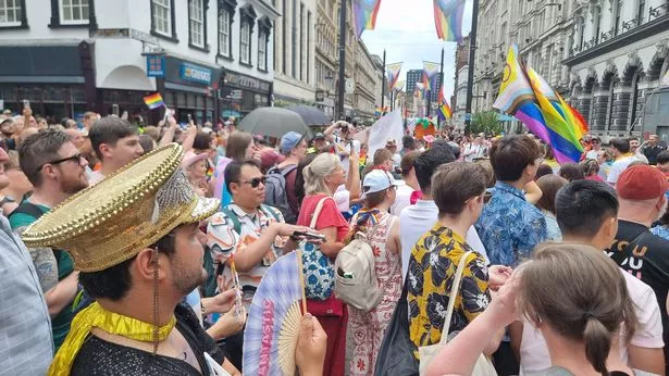 People in bright clothes on a parade through Cardiff city centre