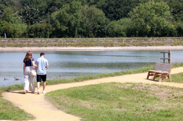 A picture of two people walking near a reservoir