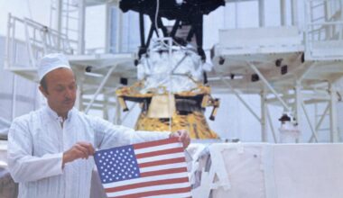 With Voyager 2 in the background, John Casani holds a small U.S. flag