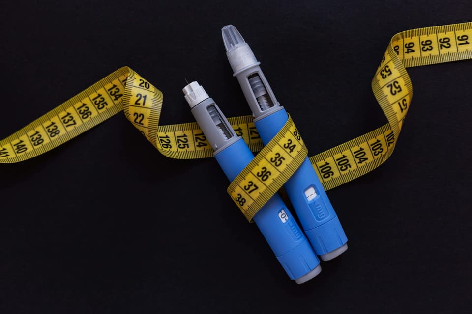 Ozempic pens wrapped around in body measurement tape