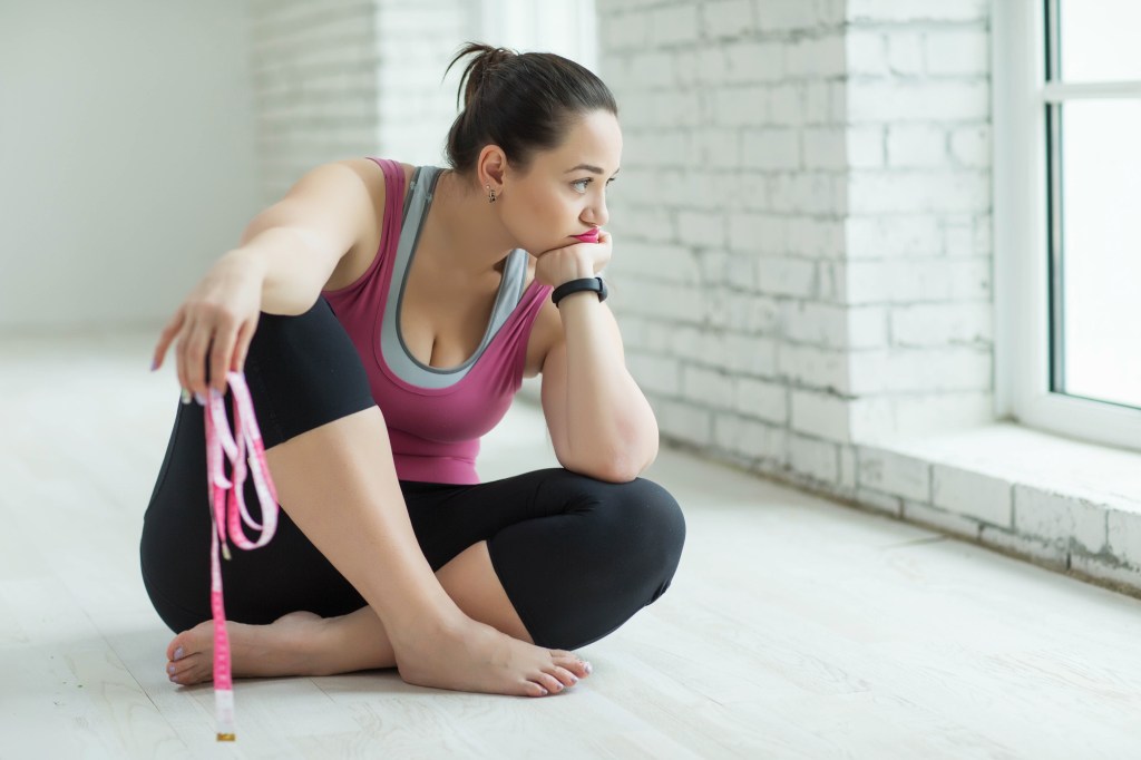 woman sitting with exercise band looking sad out the window