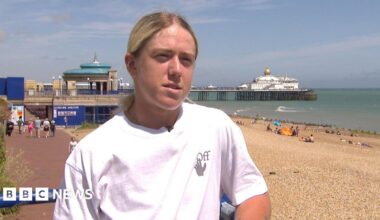 Sonay Kartal stands on Eastbourne seafront, wearing a white t-shirt, with the pier and beach in the background.