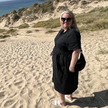 Woman in black dress on sandy beach.