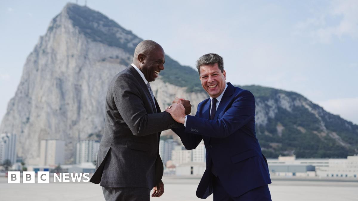 UK Foreign Secretary David Lammy and Chief Minister of Gibraltar Fabian Picardo clasp hands laughing, as they stand in front of the rock of Gibraltar.