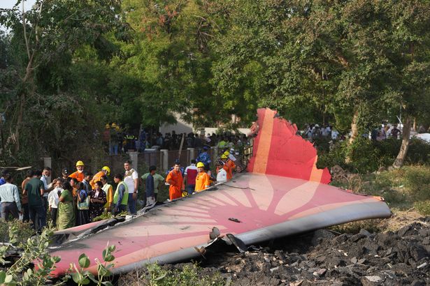 People stand around the debris of the plane after the crash