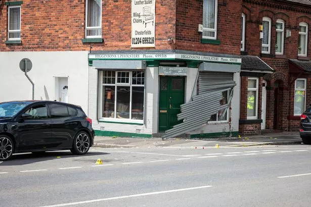 Shutters hang off the front of a shop following a crash on Chorley New Road