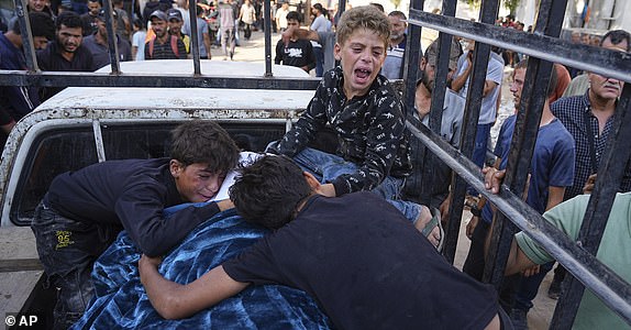 Palestinians children mourn over the body of their father, Mohammed Ghaben, who was killed while heading to an aid distribution hub, during his funeral in Gaza City, Wednesday, June 18, 2025. (AP Photo/Jehad Alshrafi)