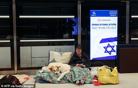 TOPSHOT - A woman accompanied by her dog, takes shelter for the night at an underground light rail station in the city of Ramat Gan, east of Tel Aviv, on June 18 2025, amid a fresh barrage of Iranian missile attacks on June 18, 2025. (Photo by AHMAD GHARABLI / AFP) (Photo by AHMAD GHARABLI/AFP via Getty Images)