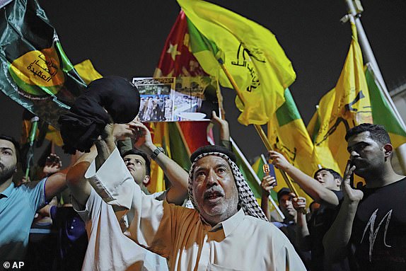 Protesters chant anti-Israel and anti-U.S. slogans during a protest against Israeli attacks on multiple cities across Iran, at a bridge leading to the fortified Green Zone where the U.S. embassy is located in Baghdad, Iraq, Wednesday, June 18, 2025. (AP Photo/Hadi Mizban)