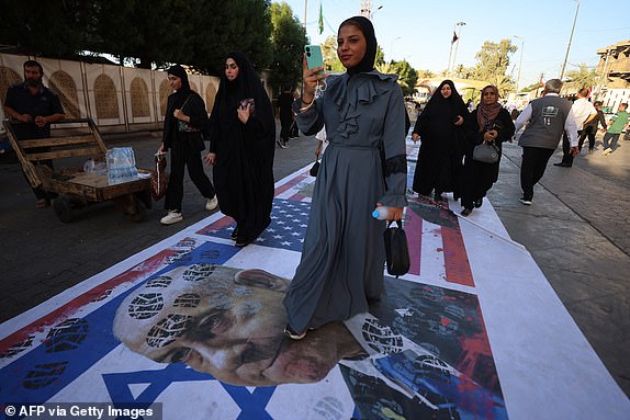 TOPSHOT - Iraqis step on a flag of Israel bearing the portrait of Israel's Prime Minister Benjamin Netanyahu during a march in the Kadhimiya district of Baghdad on June 21, 2025, to protest against Israel's strikes on Iran. (Photo by AHMAD AL-RUBAYE / AFP) (Photo by AHMAD AL-RUBAYE/AFP via Getty Images)