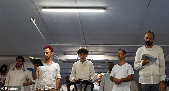 Jewish men pray at the end of Shabbat in an underground parking lot turned into a shelter amid the Iran-Israel conflict, in Tel Aviv, Israel, June 21, 2025. REUTERS/Violeta Santos Moura