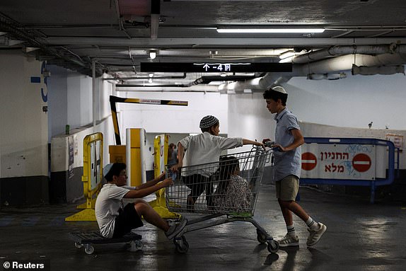Jewish children play at the entrance to an underground parking lot turned into a shelter amid the Iran-Israel conflict, in Tel Aviv, Israel, June 21, 2025. REUTERS/Violeta Santos Moura