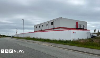 Photograph of the outside of the BCP site. It is a white building with white fencing, and "Kier" can be seen on the side of the site.