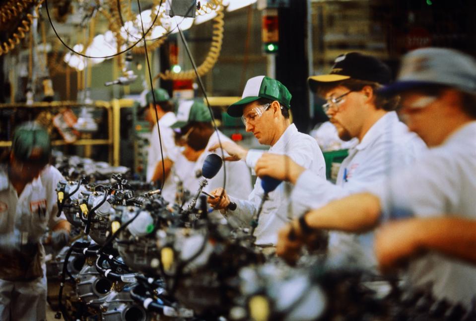 Car engine assembly, workers adjusting engine block valve