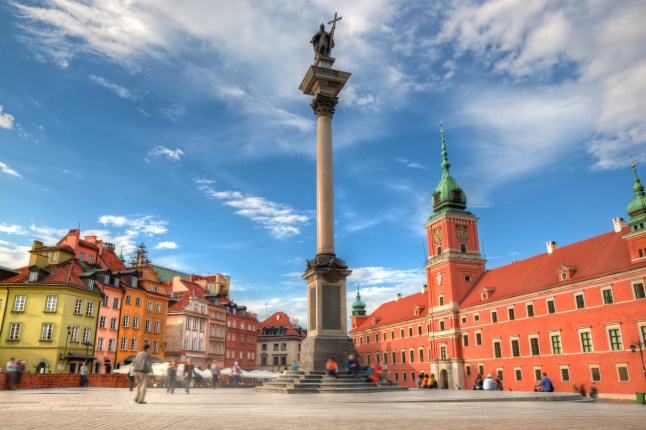 The colourful Old Town and a tall monument in Warsaw, Poland on a sunny day.