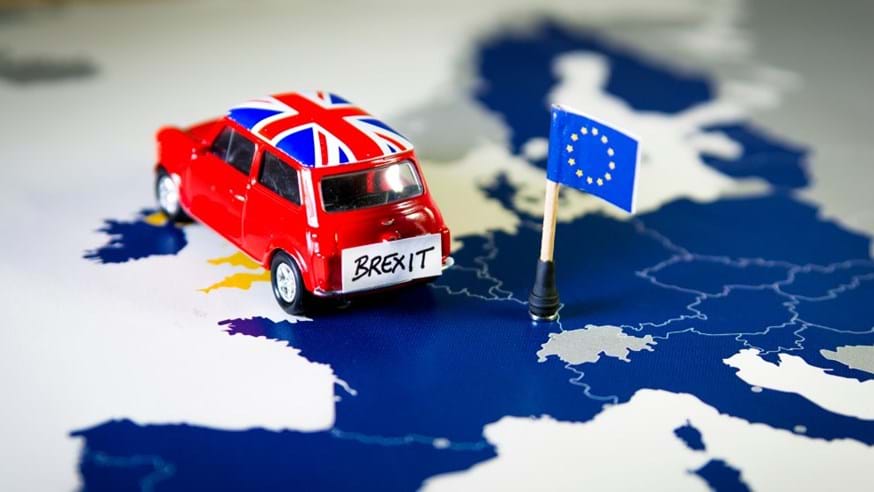 Image shows Mini car with union flag on roof and a Brexit sign on the booton a map of Europe heading from France to the UK