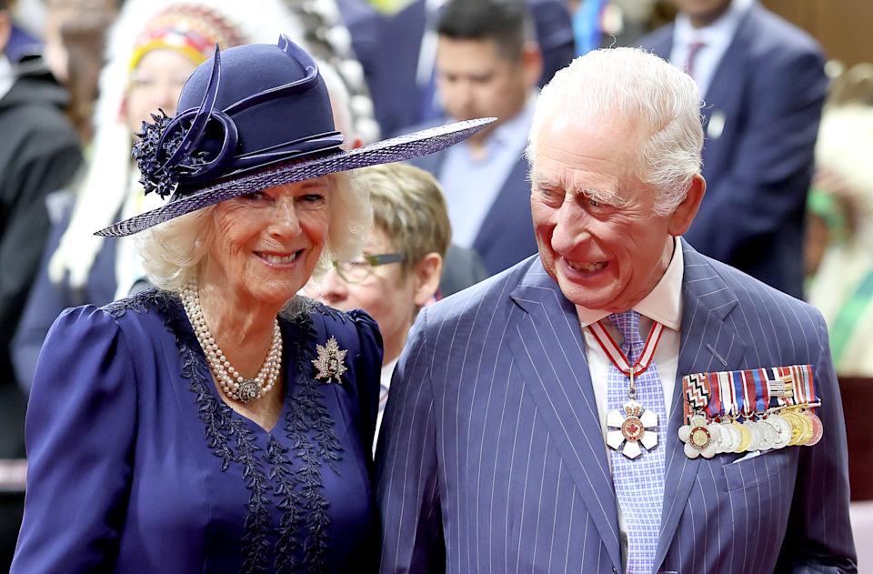 Queen Camilla and King Charles wearing blue outfits and smiling in Canada