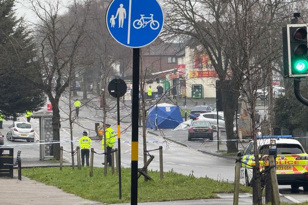 Police at the scene in Audley Road in Stechford, with a blue tent erected, six police officers pictured manning a police cordon with a police car by the side of the road and blue and white police tape surrounding the scene