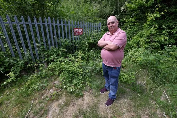 Councillor Russell Bernstein next to the fenced off plot of the former Whitefield Town Hall. 