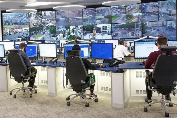 Men monitoring a huge bank of CCTV screens in an office
