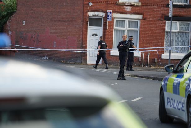 Police at the scene in Rusholme where a sergeant has his legs crushed after being rammed by a vehicle