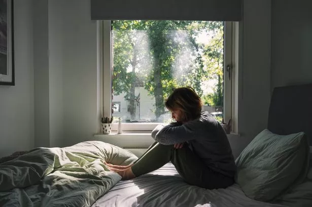 Powerful image of a mature woman sitting on her bed - negative emotions