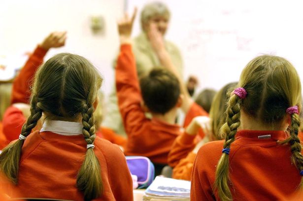 Children with their hands up in a classroom